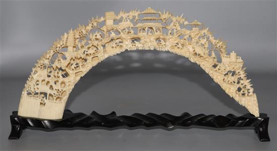 A Chinese ivory boars tusk bridge on stand, carved and pierced with figures, pagodas, trees, etc.
